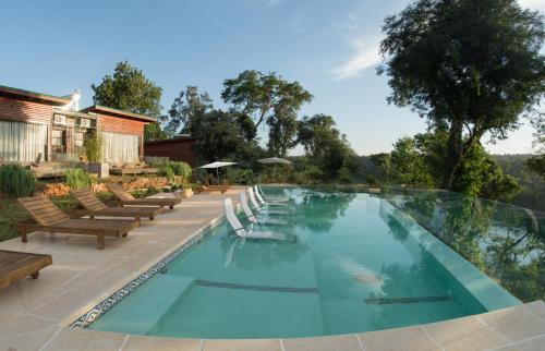 a swimming pool with chaise lounge chairs around it at Tupa Lodge in Puerto Iguazú
