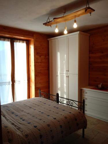 a bedroom with a bed and a white refrigerator at Appartamento L'albero e le stelle in Borgo San Dalmazzo