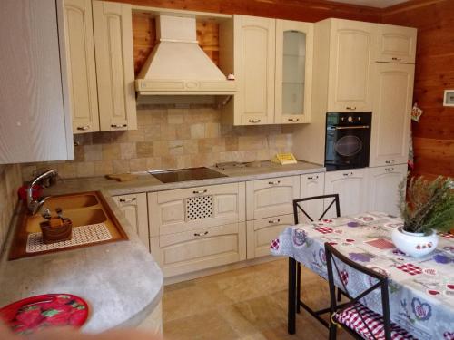 a kitchen with white cabinets and a table with a tablecloth at Appartamento L'albero e le stelle in Borgo San Dalmazzo