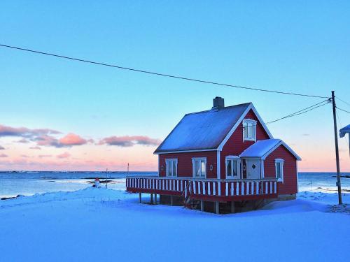 a red house with a blue roof in the snow at Beach View Lofoten in Bøstad