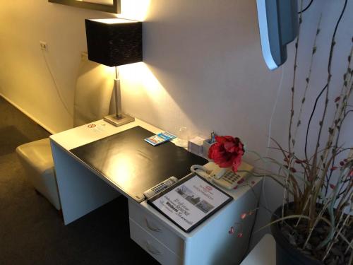 a desk with a lamp and a plant on it at Hotel de Keizerskroon Hoorn in Hoorn