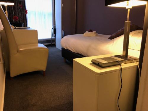 a hotel room with a bed and a lamp and a chair at Hotel de Keizerskroon Hoorn in Hoorn