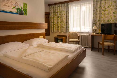 Schlafzimmer mit einem Bett, einem Schreibtisch und einem TV in der Unterkunft Hotel Anker in Klosterneuburg
