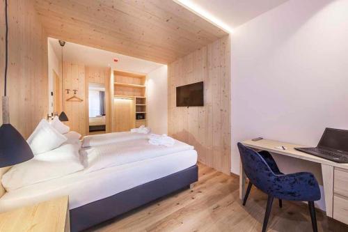 a bedroom with a bed and a desk with a laptop at Hotel Garni Broi - Charme & Relax in Selva di Val Gardena