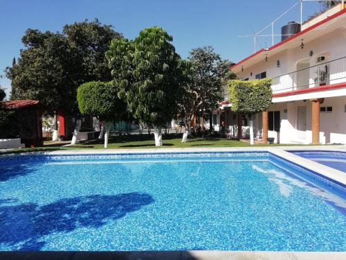 a blue swimming pool in front of a building at Hotel Quinta Paraiso in Cocoyoc