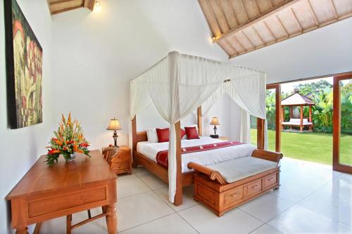 a bedroom with a canopy bed and a desk at Villa Nico - Private Pool with Onsite Spa in Canggu
