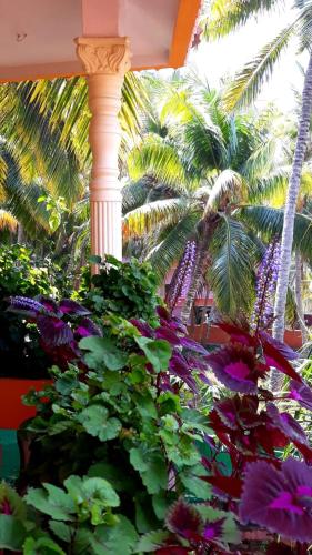 a column with flowers and palm trees in a garden at Thriphala Ayurveda Yogashram in Trivandrum