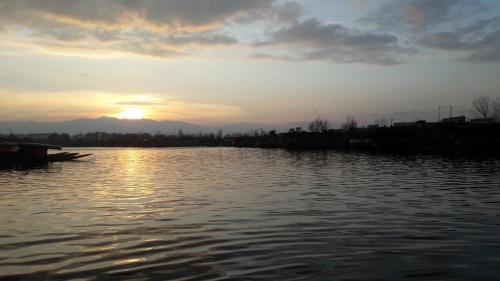 a sunset over a body of water with a boat at Goona palace houseboats in Srinagar