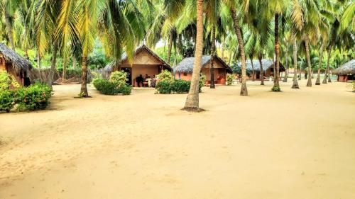 a group of palm trees on a beach with houses at Roshanne Beach Resort in Kalpitiya