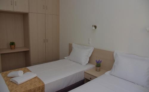 two beds in a small bedroom with white cabinets at LEONIDIO APARTMENT SELINI in Leonidion