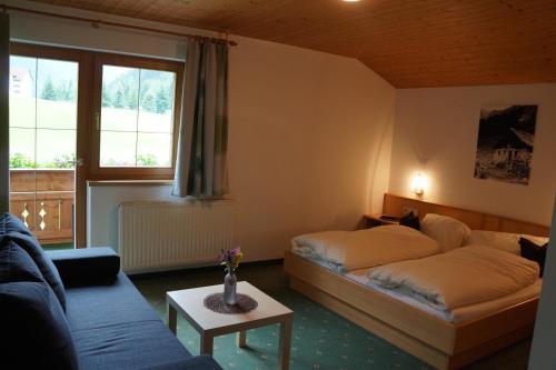 Zimmer mit 2 Betten, einem Sofa und einem Fenster in der Unterkunft Bergfeuerhof in Kaunertal