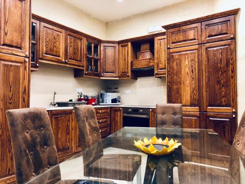 スリーマにあるModern Maltese Houseのキッチン(ガラステーブル、木製キャビネット付)