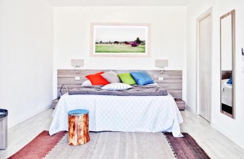 a bedroom with a bed with colorful pillows at Hotel Botanic Golf SaCuba in Olbia