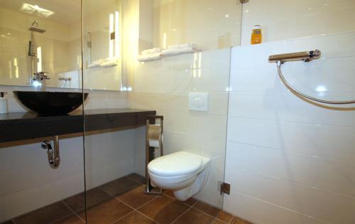 a white bathroom with a toilet and a sink at Hotel Helena in Neu Wulmstorf