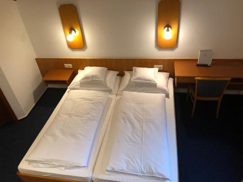 a room with two beds and a desk and a table with a chair at Gasthof Zur Krone in Leidersbach