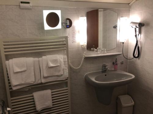 a bathroom with a sink and a mirror and towels at Gasthof Zur Krone in Leidersbach