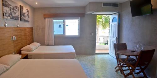 Habitación de hotel con 2 camas, mesa y ventana en Hotel Rio Malecon en Puerto Vallarta