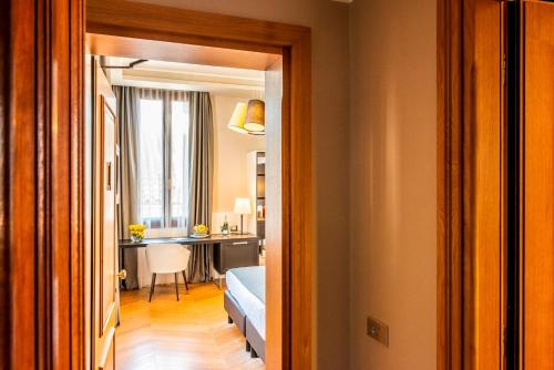 a hallway leading to a room with a bedroom and a desk at Hotel Grande Italia in Chioggia