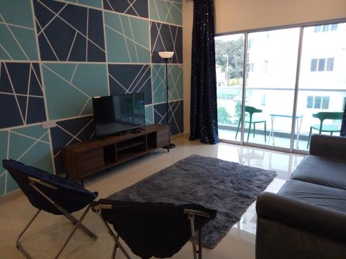 a living room with a couch and a table and a tv at ICOLOR HOME & STAY CH3 in Tanah Rata