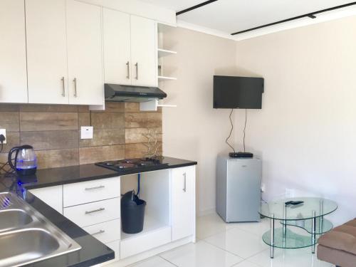 a kitchen with white cabinets and a small refrigerator at Man Cave Suite in Swakopmund