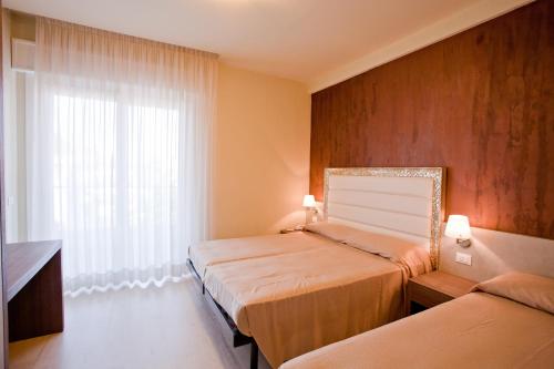 a hotel room with two beds and a window at Residence Elisabetta in Cesenatico
