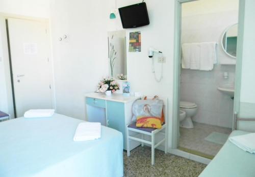 La salle de bains est pourvue de 2 lits, d'un lavabo et d'un miroir. dans l'établissement Hotel Urania, à Rimini