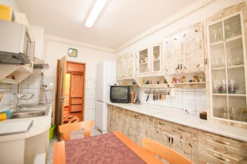 a kitchen with white cabinets and a sink and a television at Apartament Happynest in Predeal