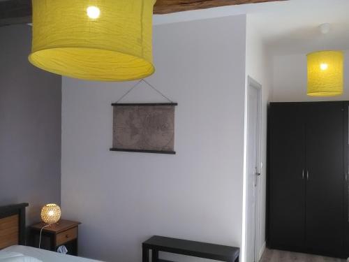 a bedroom with a yellow light hanging from the ceiling at A deux pas du Rheby in Villebois