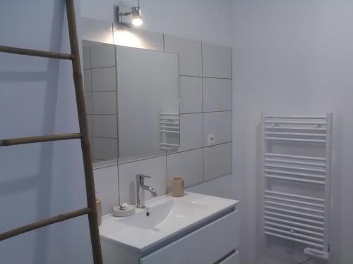 ein weißes Badezimmer mit einem Waschbecken und einem Spiegel in der Unterkunft A deux pas du Rheby in Villebois