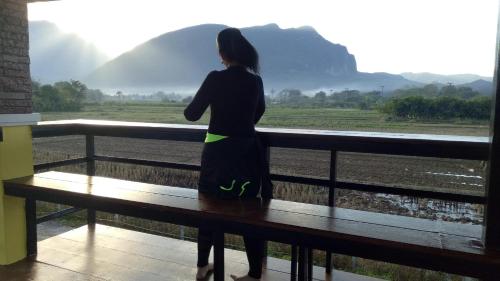 a woman standing on a bench looking out at a view at Ban Thung Talay Mok Chiangdao in Chiang Dao