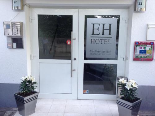 a door to a hotel with two plants in front of it at Hotel Eschborner Hof in Frankfurt/Main
