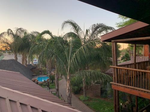 a balcony of a house with palm trees and a pool at Country Lodge in Upington