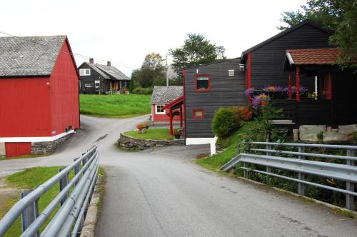 a village with red and black buildings and a road at Haugo Utleige Lodge in Vossevangen