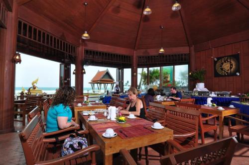 a group of people sitting at tables in a restaurant at Baan Karonburi Resort in Karon Beach