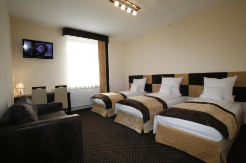 Habitación de hotel con 3 camas y sofá en Boutique Hotel's I en Lodz