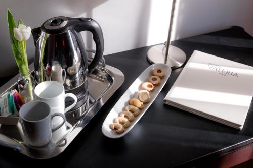 a black table with a tray of donuts and a tea kettle at Hotel Valeria in Villa Opicina