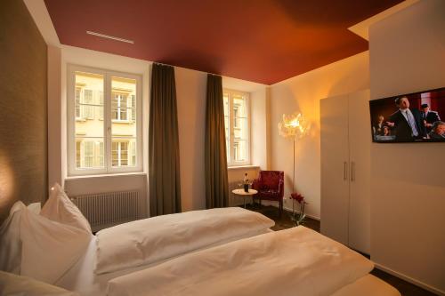 1 Schlafzimmer mit 2 weißen Betten und einem TV in der Unterkunft Boutique Hotel - Restaurant Orchidee in Burgdorf