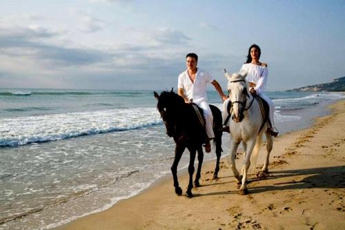 a man and woman riding horses on the beach at Hotel Magnific in Kranevo