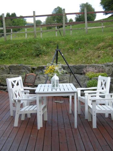 a white picnic table and two chairs on a deck at Skjerping gård in Lonevåg