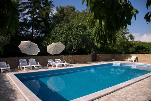 a swimming pool with two umbrellas and chairs and umbrellas at Sanja apartments Sveti Servul in Novigrad Istria