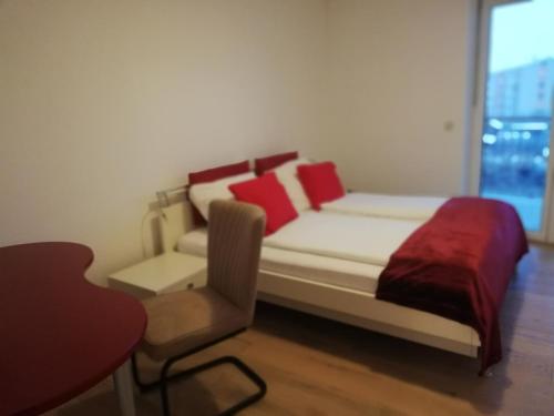 a bedroom with a bed and a chair and a window at APARTMENT SCHLOSSBERGBLICK in Graz