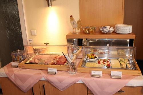 a table with two trays of food and a bird on it at Hotel Adlerhof in Tauberbischofsheim