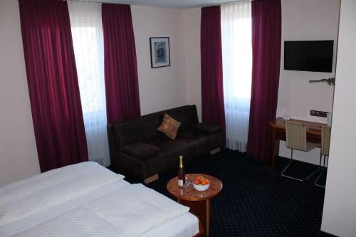 a hotel room with a bed and a chair at Hotel Adlerhof in Tauberbischofsheim