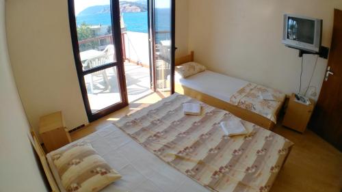 een kamer met 2 bedden en een balkon met een televisie bij Guesthouse Obala in Sutomore