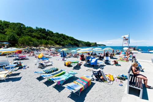 a crowd of people on a beach with chairs and umbrellas at Hotel Mirta - San Simon Resort in Izola