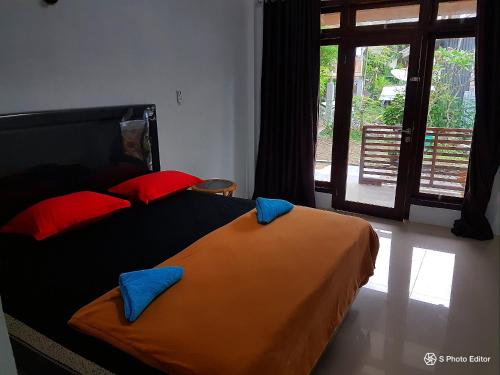 Schlafzimmer mit einem Bett mit roten und blauen Kissen in der Unterkunft Iboih Malini Bungalow in Sabang