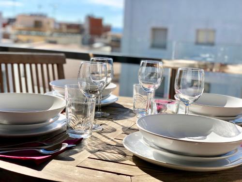 a wooden table with plates and wine glasses on it at Apartament Familiar Av. Tarragona in Roses