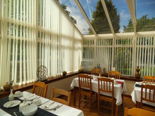 a dining room with white tables and chairs and windows at Northumberland Hotel in Edinburgh