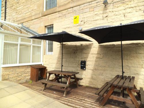 a picnic table and benches with umbrellas on a patio at Northumberland Hotel in Edinburgh