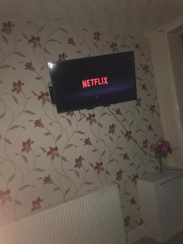 a television on a wall with flowers on a wall at Entire B&B in Burnley